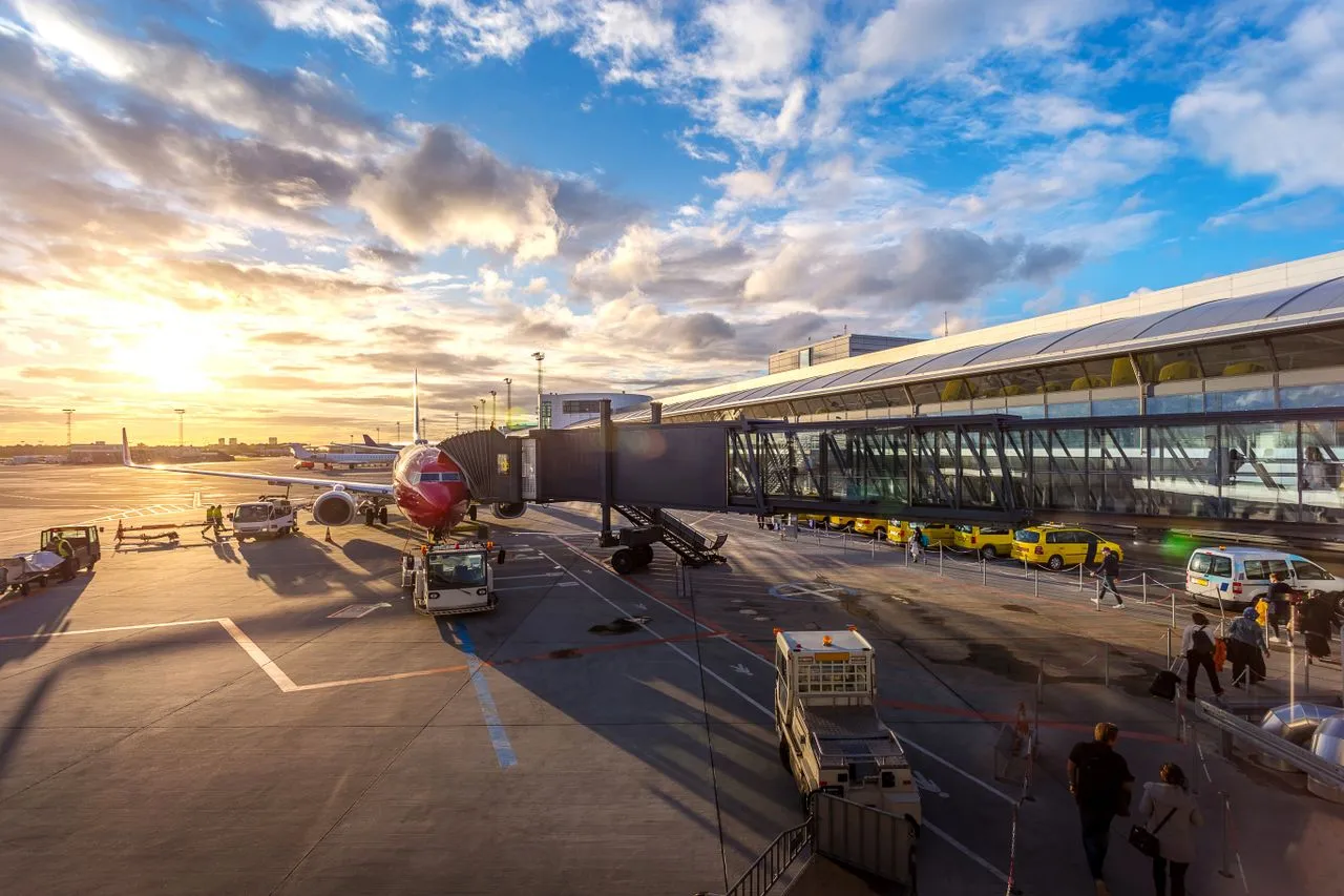 Traveler checking flight deals on phone in departure lounge with boarding pass and passport