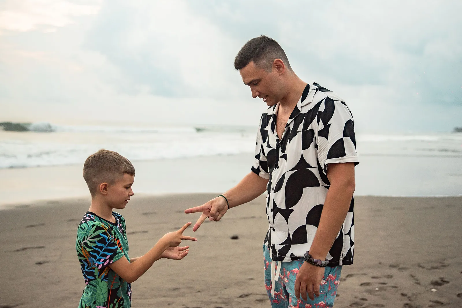 Father and young son playing together on a wide sandy beach in Bali