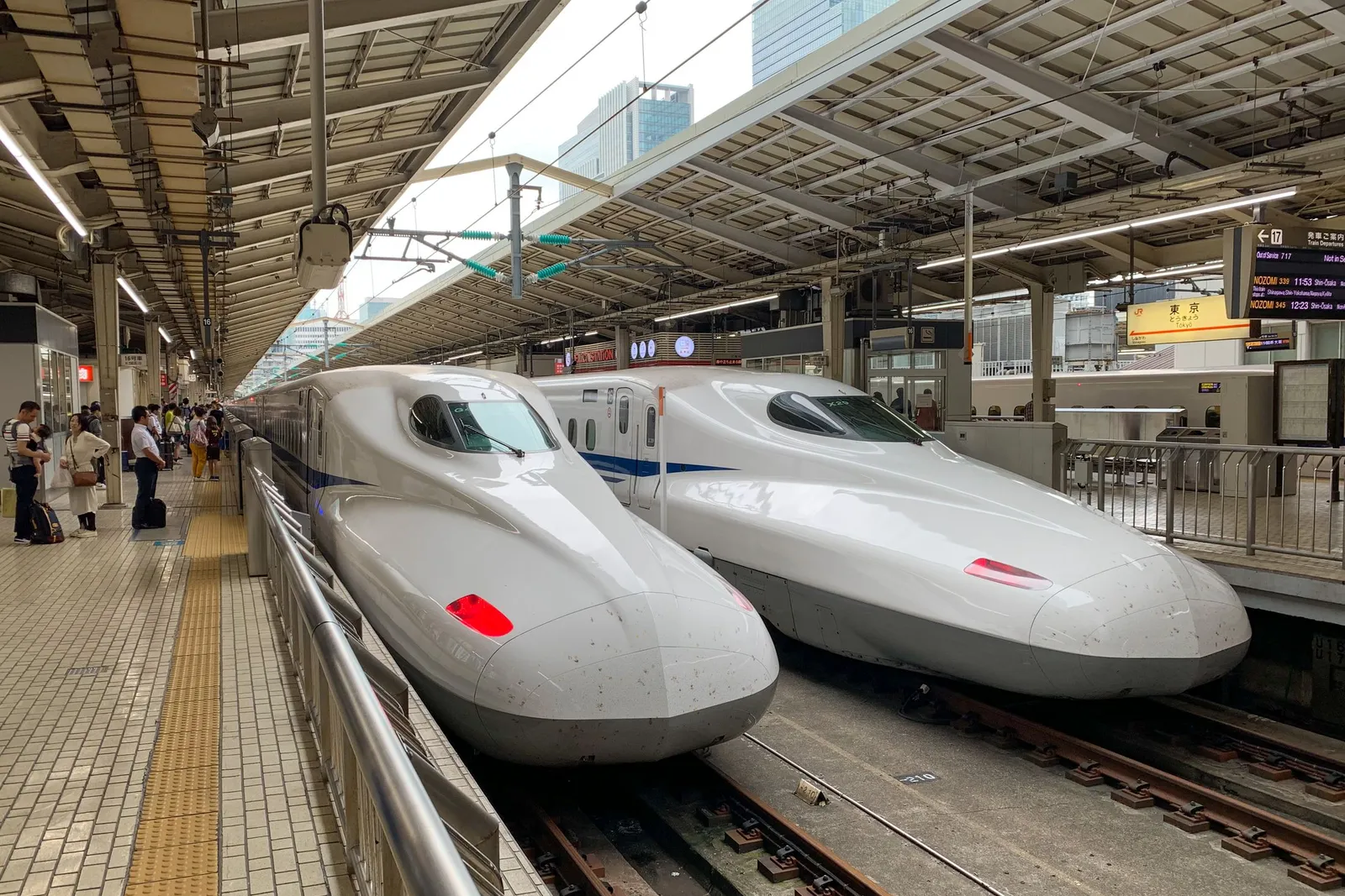 Two white Shinkansen bullet trains waiting at a platform at Tokyo Station