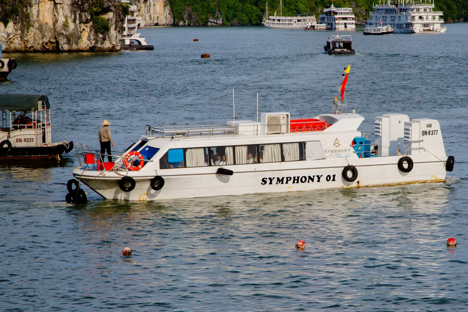 Tourist cruise boat on the calm water of Ha Long Bay in Vietnam with limestone karsts behind it