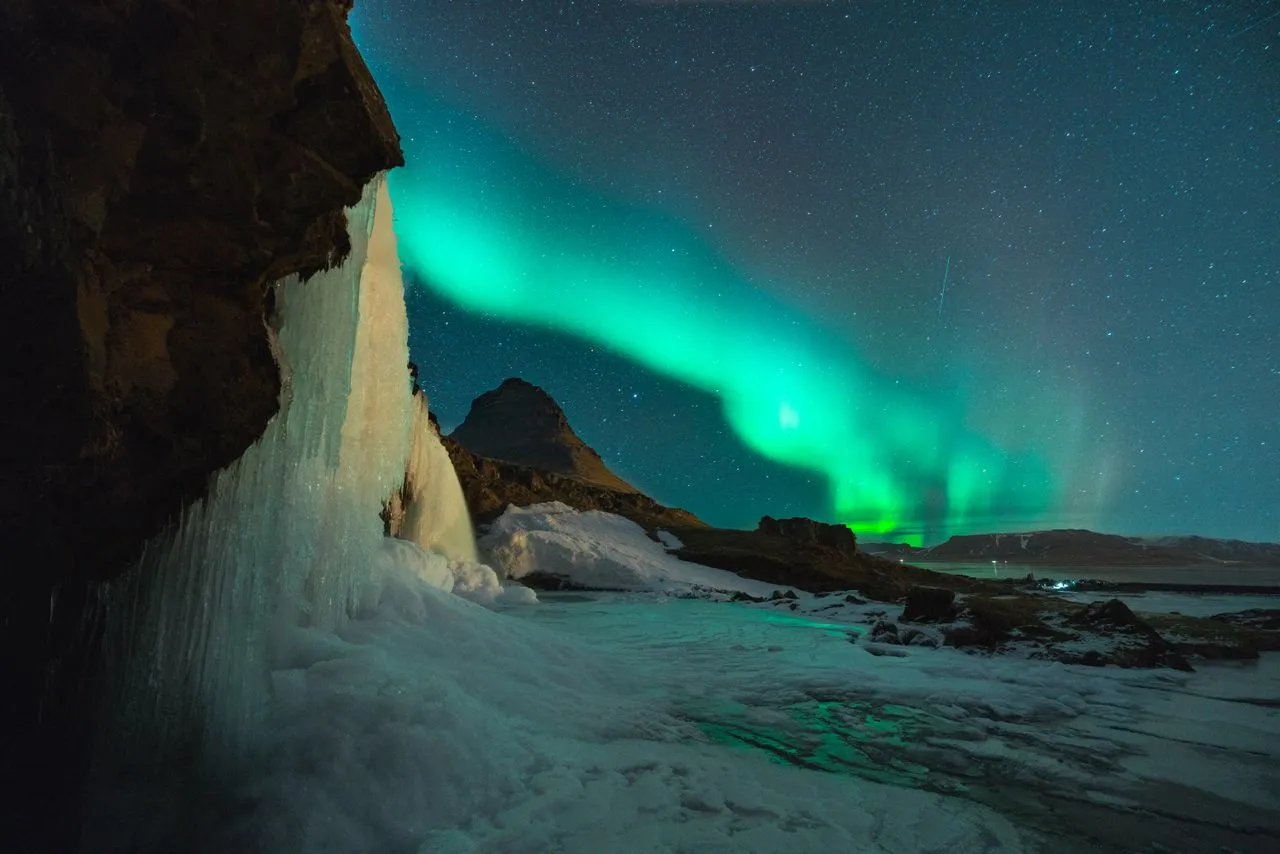 Iceland's Ring Road winding through moss-covered lava fields with snow-capped mountains in the distance under a summer midnight-sun sky