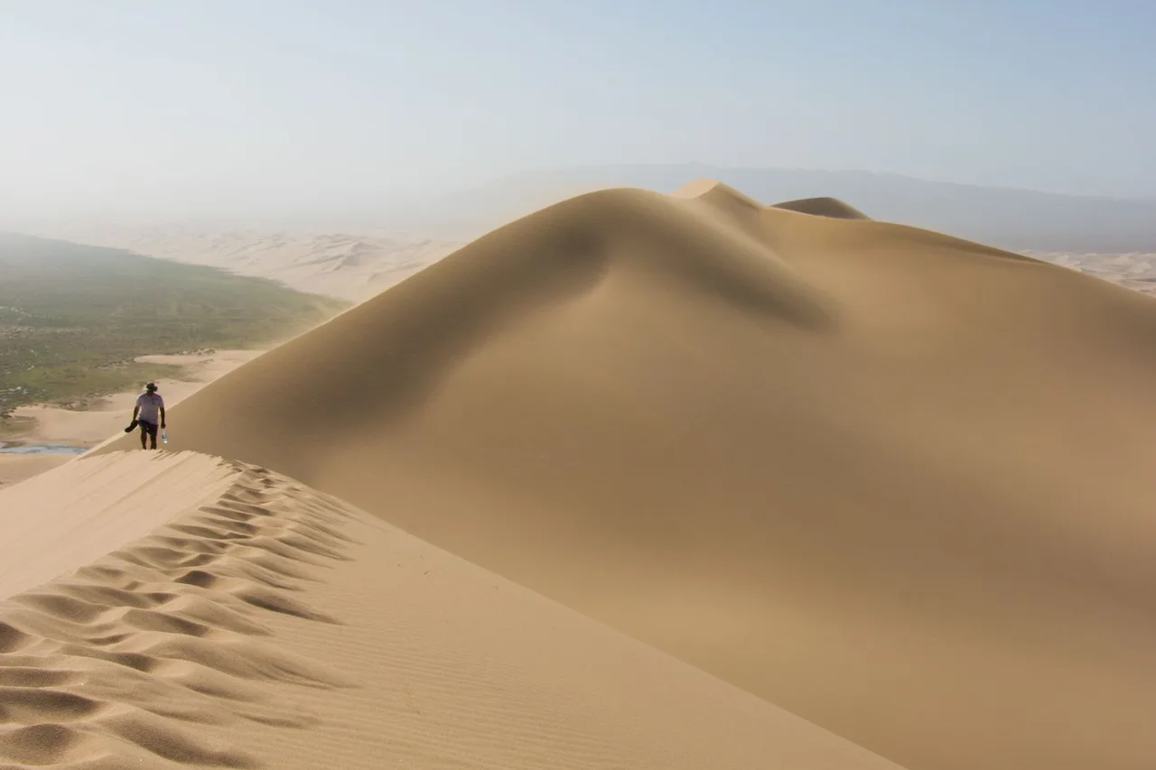 A traveller walking along the ridge of a towering sand dune in the Gobi Desert near Nomgon, Mongolia