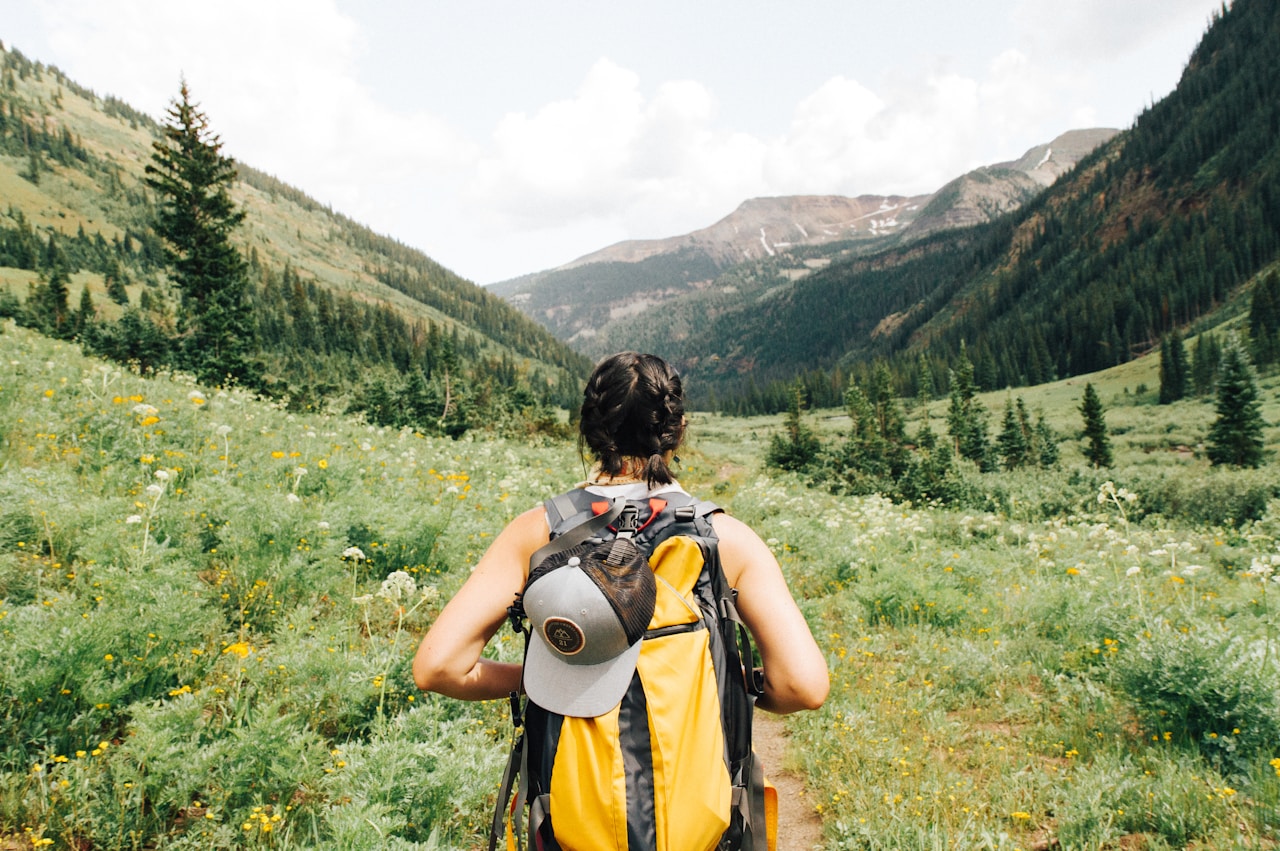 Solo traveller with backpack looking at mountain landscape at sunrise