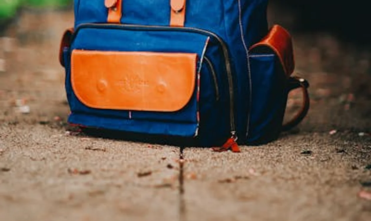 A vintage leather weekend bag photographed on a hotel bench beside a folded jacket