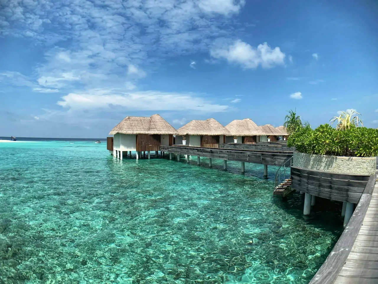 Maldives aerial view of turquoise lagoon, white sand overwater bungalows, and coral reef from above